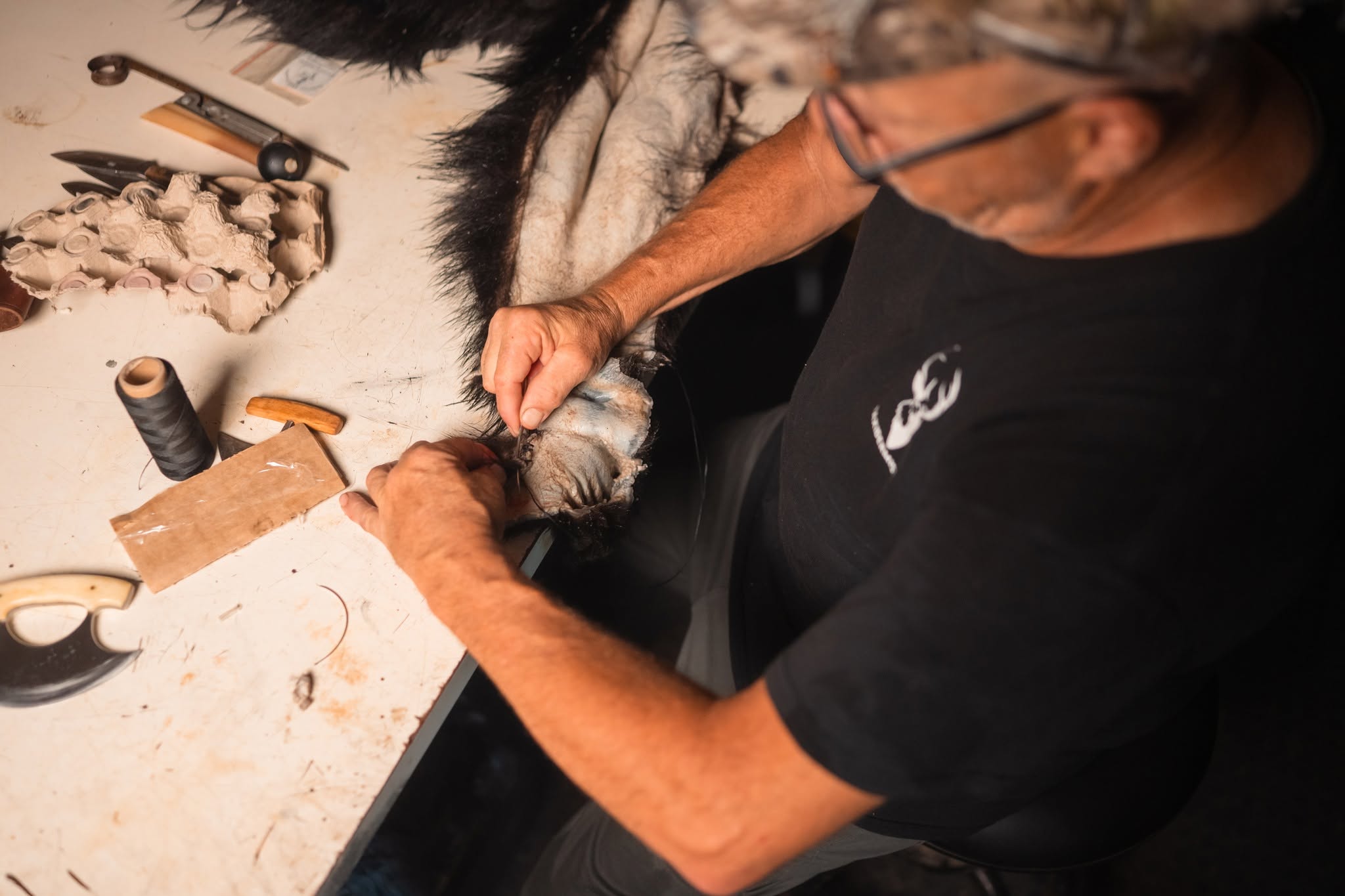Mains de Stéphane Canuel amincissant une peau à la main, étape du shaving
